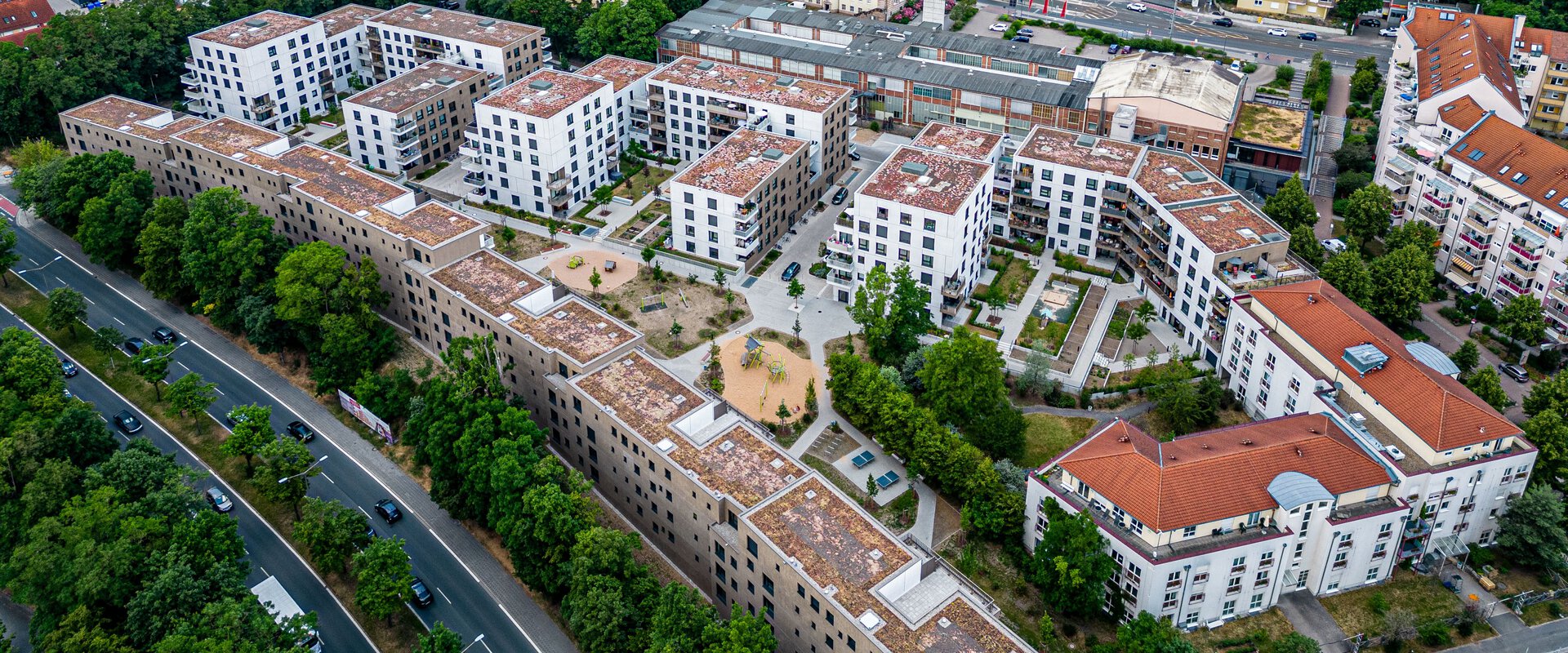 Luftaufnahme des Quartiers Tafel in Nürnberg, zeigt neu errichtete, weiße Wohngebäude, die sich in eine bestehende städtische Umgebung mit Grünflächen einfügen. 