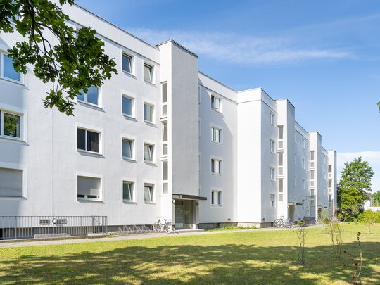 Außenansicht Kaufobjekt in Fürstenfeldbruck. Weiße Fassade mit Außenfahrstühlen direkt neben den Eingängen