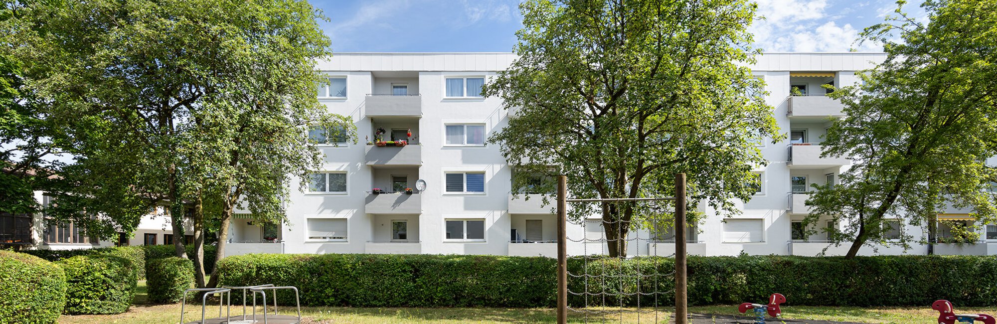 Wohngebäude mit Balkonen ausgerichtet auf eine Grünanlage mit Spielplatz