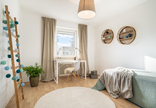 Helles Kinderzimmer mit Einzelbett und Schreibtisch vor dem Fenster